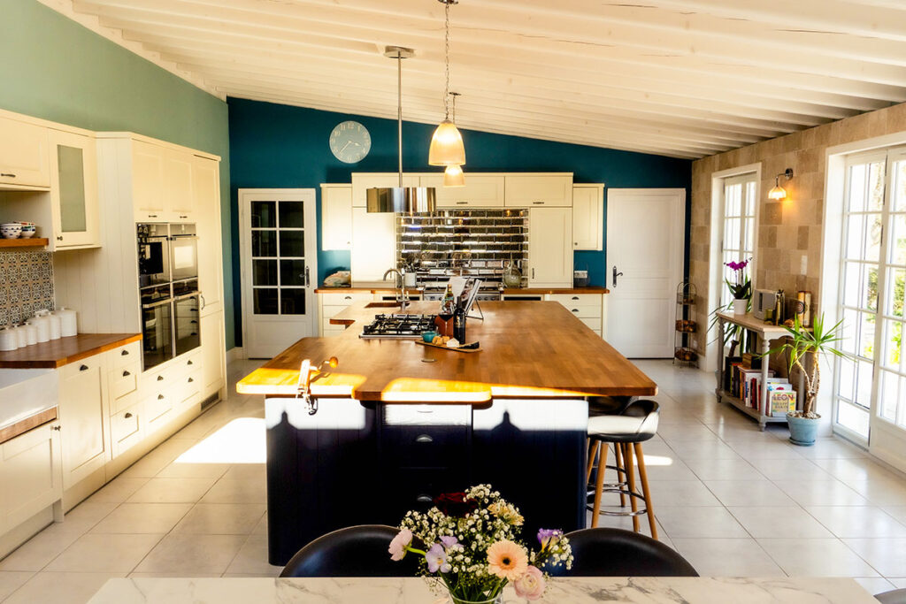 Modern and colourful kitchen with a large island at Logis de Tirac, illuminated by bright sunlight